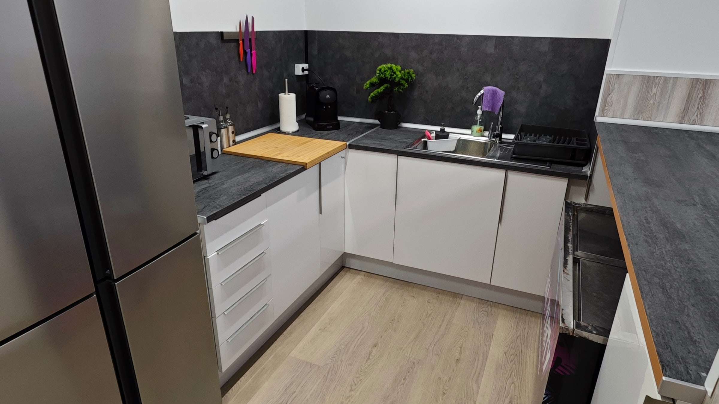 Cocina con encimera, fregadero, cafetera y armarios blancos