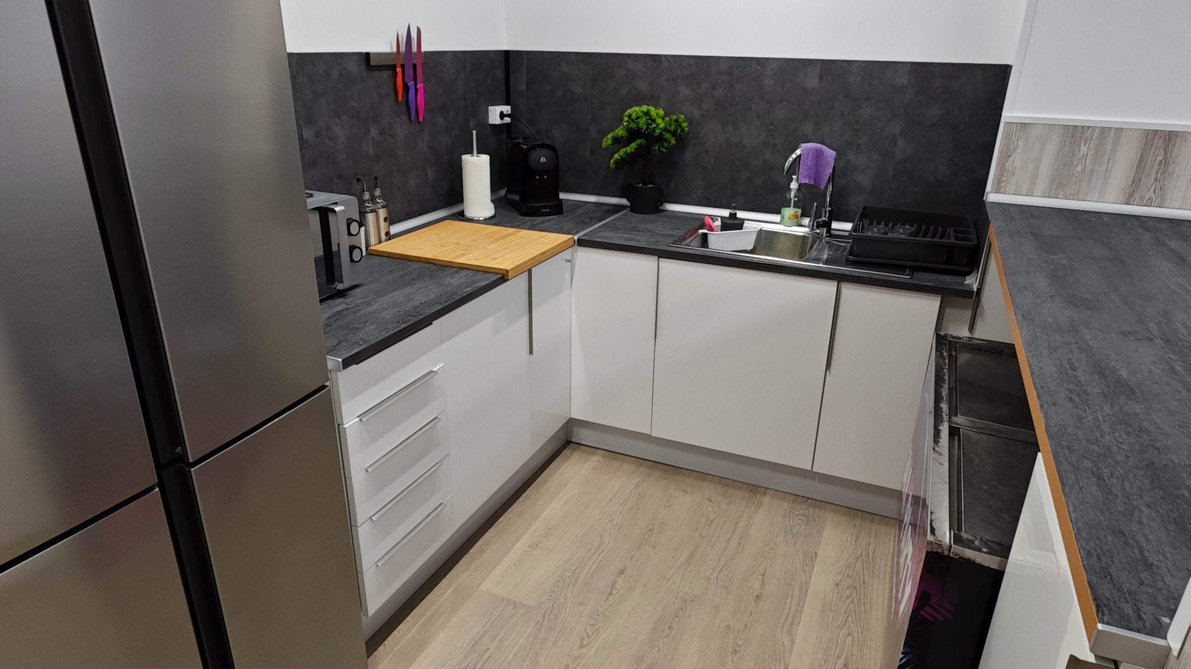 Cocina con encimera, fregadero, cafetera y armarios blancos